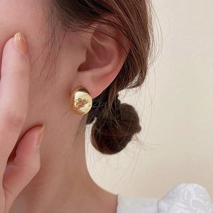 Close-up of a model wearing a minimalist gold-plated teardrop stud earring with smooth finish