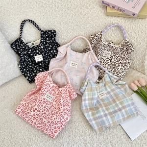 Vue à plat de divers sacs cabas en toile florale avec boutons pressions sur peluche
