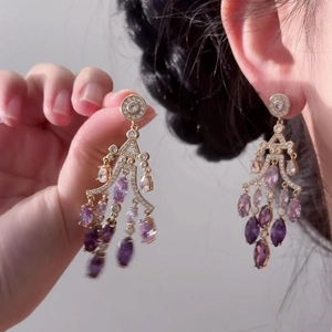 Detail of 18K gold-plated drop earrings featuring teardrop purple zircon gemstones