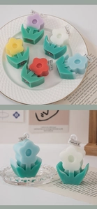 Detailed view of colorful flower shaped scented candles on a gold-rimmed white plate