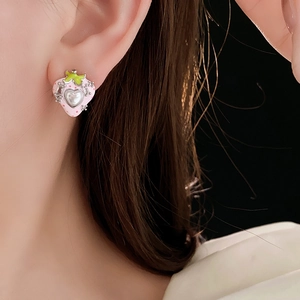 Makroaufnahme von Erdbeer-Ohrringen mit Herzperle am Ohr des Models