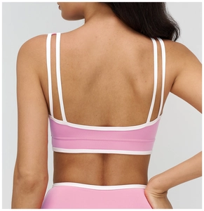 Close-up of pink yoga bra featuring white double straps and contrast edge detail