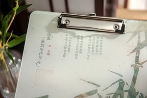 Close-up of a light green acrylic clipboard featuring Su Shi's poem and bamboo motifs