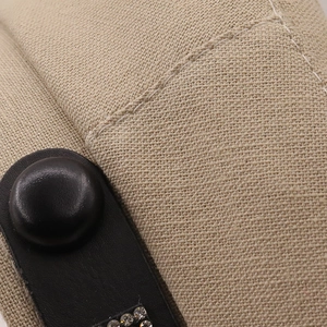 Macro detail of beige woven fabric with black leather trim and sparkling rhinestones