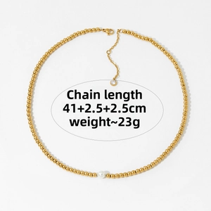 Detail of gold beaded necklace with a white pearl charm and lobster clasp closure