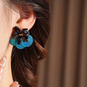 Detail shot of vintage style flower earring with blue sequins and black beads on model