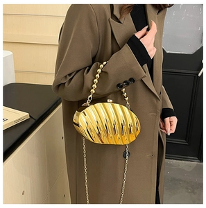 Detailed view of gold evening clutch with wave texture and beaded handle for formal events