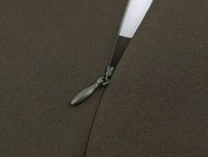 Detailed macro shot of the invisible zipper closure on an olive green midi dress