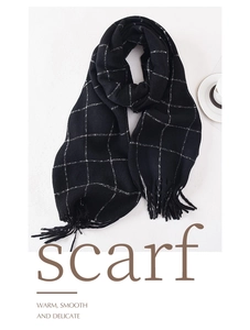 Detail of a black and white windowpane plaid scarf with fringes on a minimalist background