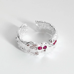 Close-up of irregular textured 925 silver ring with four red gemstones on white background