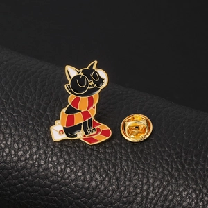 Detailed close-up of a black cat enamel pin wearing a red and yellow scarf on leather