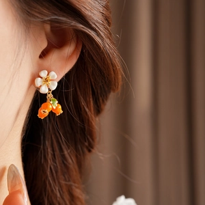 Close-up of vintage flower and berry drop earrings worn on a model's ear
