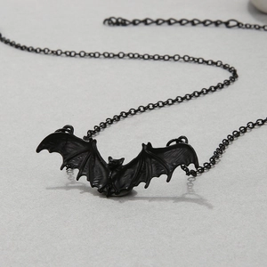 Gothic punk black metal bat pendant necklace for women on a grey textured background