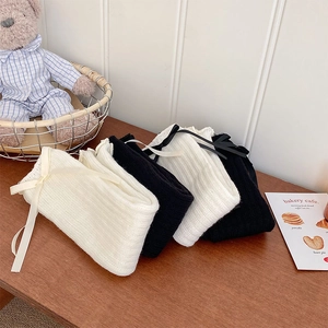 Close-up of ribbed knit leg warmers with delicate satin ribbon bows in cream and black