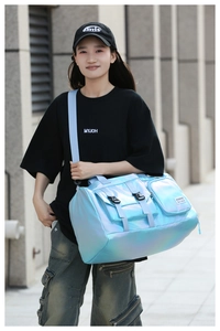 Model showcasing a large holographic light blue fitness bag in an urban street setting