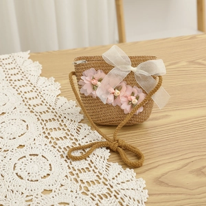 Vue détaillée du sac bandoulière en paille avec fleurs roses et nœud en organza blanc élégant