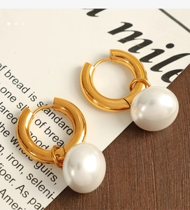Detailed view of gold hoop earrings with white pearl pendants on vintage paper background