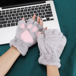 Close-up of grey plush cat paw fingerless gloves on laptop showing pink paw pad details