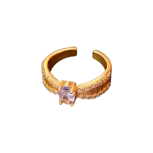Verstellbarer Goldring mit lila Zirkon und strukturierter Schiene auf weißem Grund