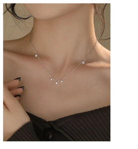 Detail of silver S925 sterling silver necklace with five sparkling zircon stones on a model