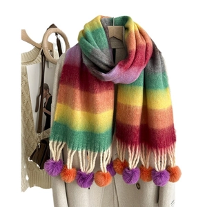 Rainbow striped mohair scarf with purple and orange pompoms styled on a beige coat