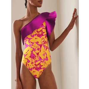 Detail of ruffled one-shoulder swimsuit featuring vibrant tropical floral prints