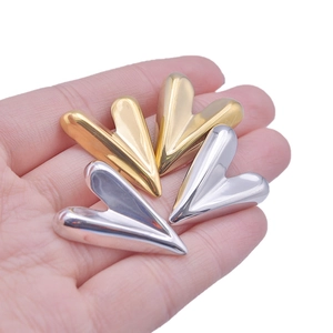 Macro detail of 3D geometric heart earrings in polished gold and silver finish