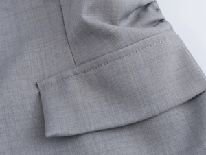 Gros plan sur la texture du tissu gris du blazer et le rabat de poche de l'ensemble