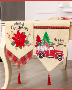 Detail of linen Christmas table runner featuring red truck, poinsettia, and tassels
