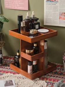 Close-up of a rotating two-tier dark brown wooden cosmetic organizer on an ethnic tablecloth