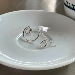 Minimalist 925 sterling silver asymmetrical spiral stud earrings in a white ceramic dish