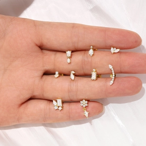 Détails de divers clous d'oreilles en argent S925 doré avec zircons brillants sur la main