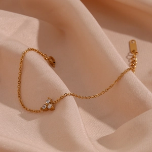 Macro shot of gold-plated bracelet featuring three sparkling zircons on elegant silk