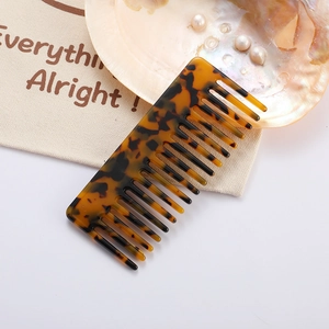 Close-up of tortoise shell acetate hair comb on canvas bag with shell and pearls