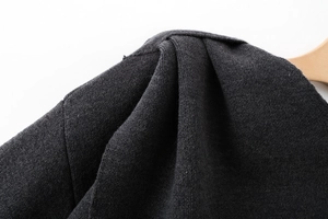 Close-up of pleated shoulder detail on high-quality dark grey knitted scarf cloak poncho