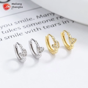 Detailed view of silver and gold heart-shaped huggie earrings with sparkling zircons