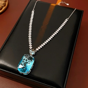Detail shot of a square blue gemstone pendant necklace on a black jewelry box