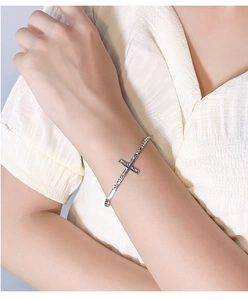 Close-up of a silver cross bracelet for women with minimalist textured design