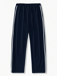Close-up of navy blue joggers with white side stripes and elastic waistband on plain background
