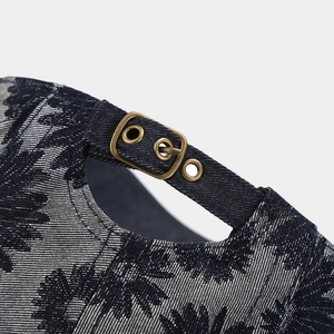 Detailed close-up of navy daisy denim cap with bronze metal adjustable buckle strap
