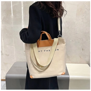 Detail of beige canvas tote with brown leather straps and a detachable shoulder strap