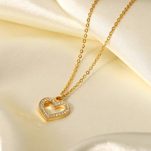 Close-up of 18K gold plated heart pendant with sparkling cubic zirconia on silk fabric
