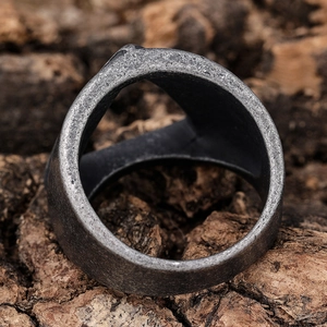 Gros plan d'une bague en acier inoxydable gris mat au style rétro sur fond de bois