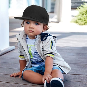 Toddler wearing a black flat-brim snapback baseball cap in a minimalist studio setting