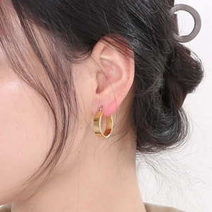 Detail view of a wide surface gold U-shaped hoop earring made of stainless steel