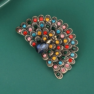 Detailed close-up of a vintage peacock brooch with colorful crystals and a blue gemstone