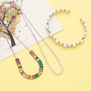 Detailed view of silver zircon necklace and cutout bracelet set on yellow background