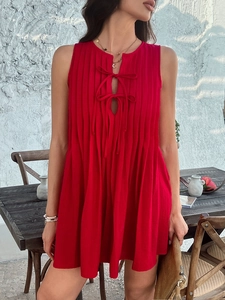 Detail of red sleeveless pleated mini dress featuring a cutout neckline with tie-up closure