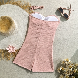 Detail of pink one-piece swimsuit with textured fabric, padded cups and beach accessories