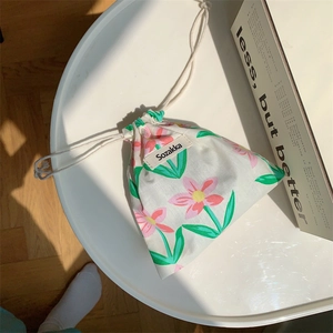 Detail of floral fabric drawstring pouch with Sozakka label on a white table surface
